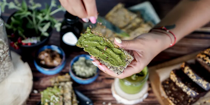 Woman preparing healthy snacks with crispbread and greens