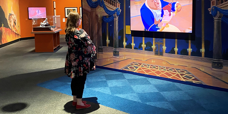 Sabina standing, watching Beauty and the Beast at an exhibition
